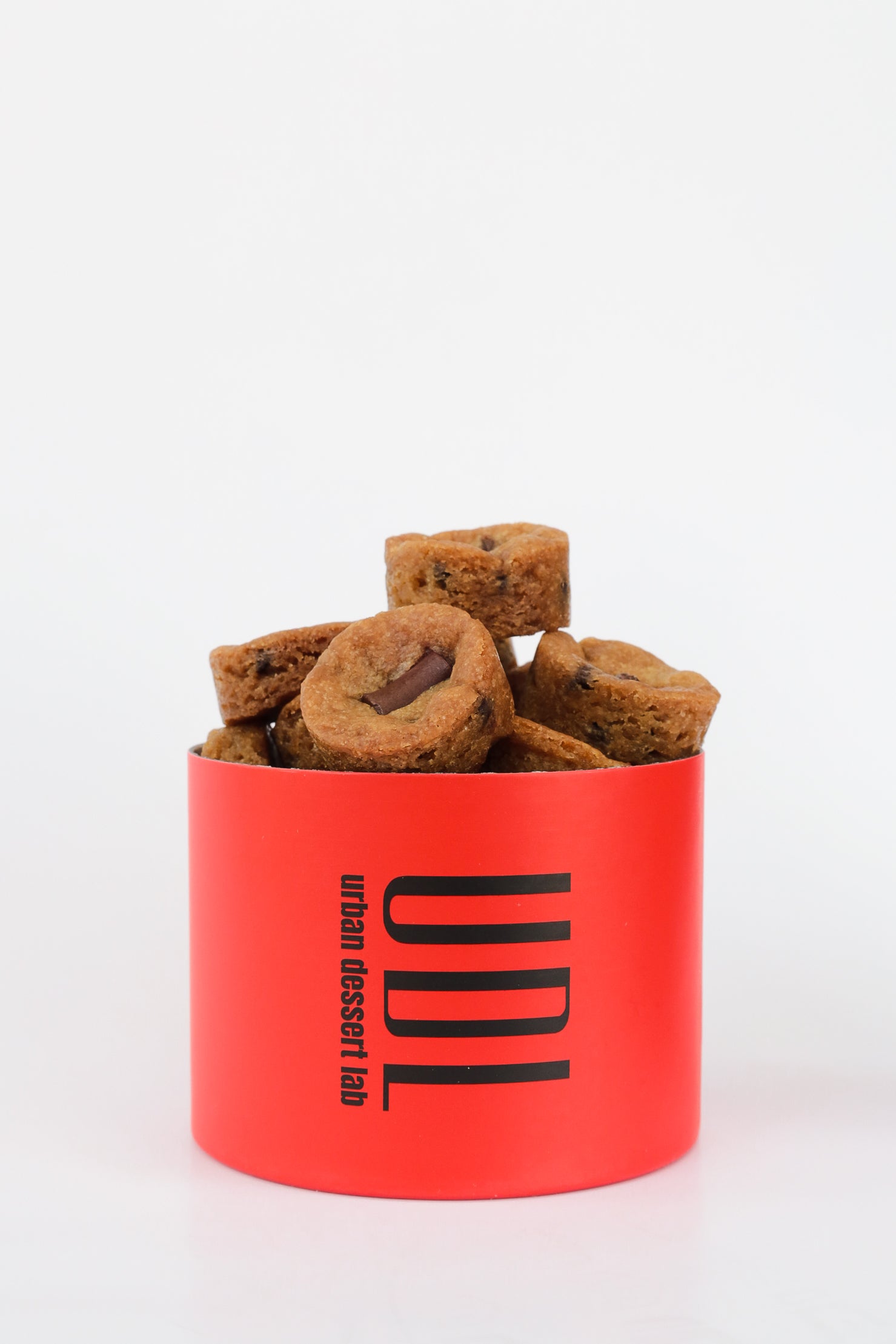 A bright red cylindrical container labeled "UDL" with petite cookies inside.