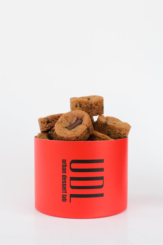 A bright red cylindrical container labeled "UDL" with petite cookies inside.