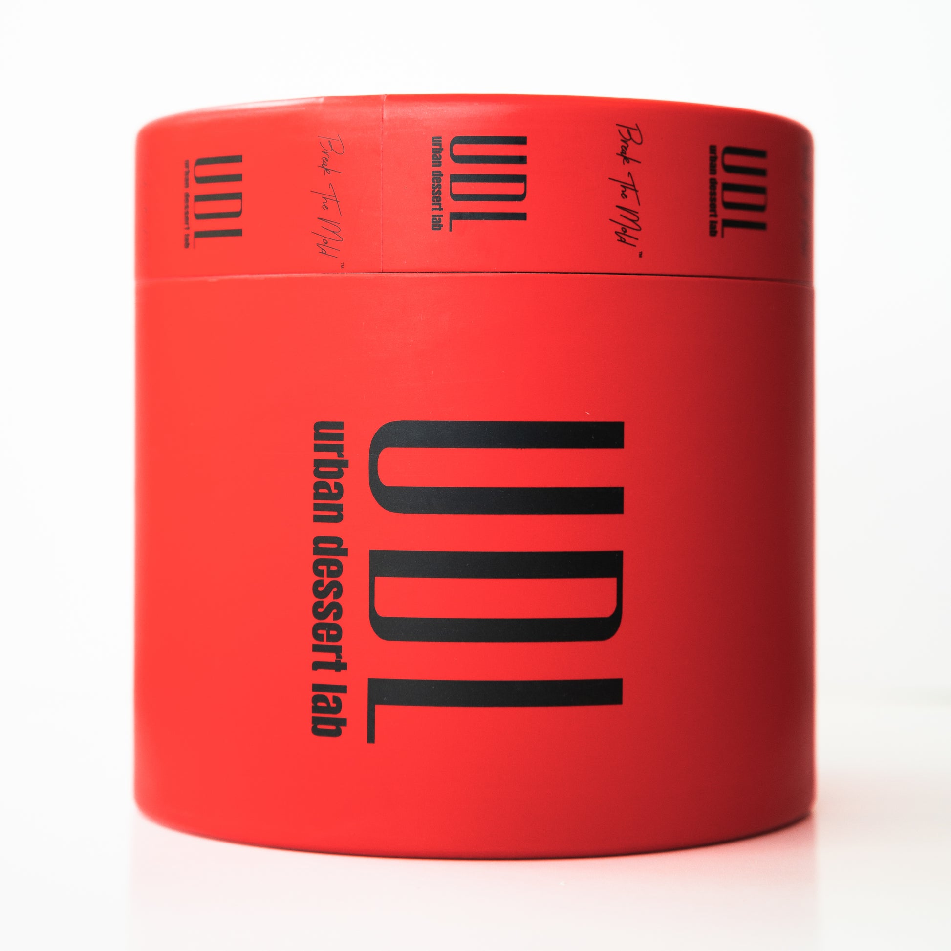 A bright red cylindrical container labeled "UDL" and "urban dessert lab" in bold black text.