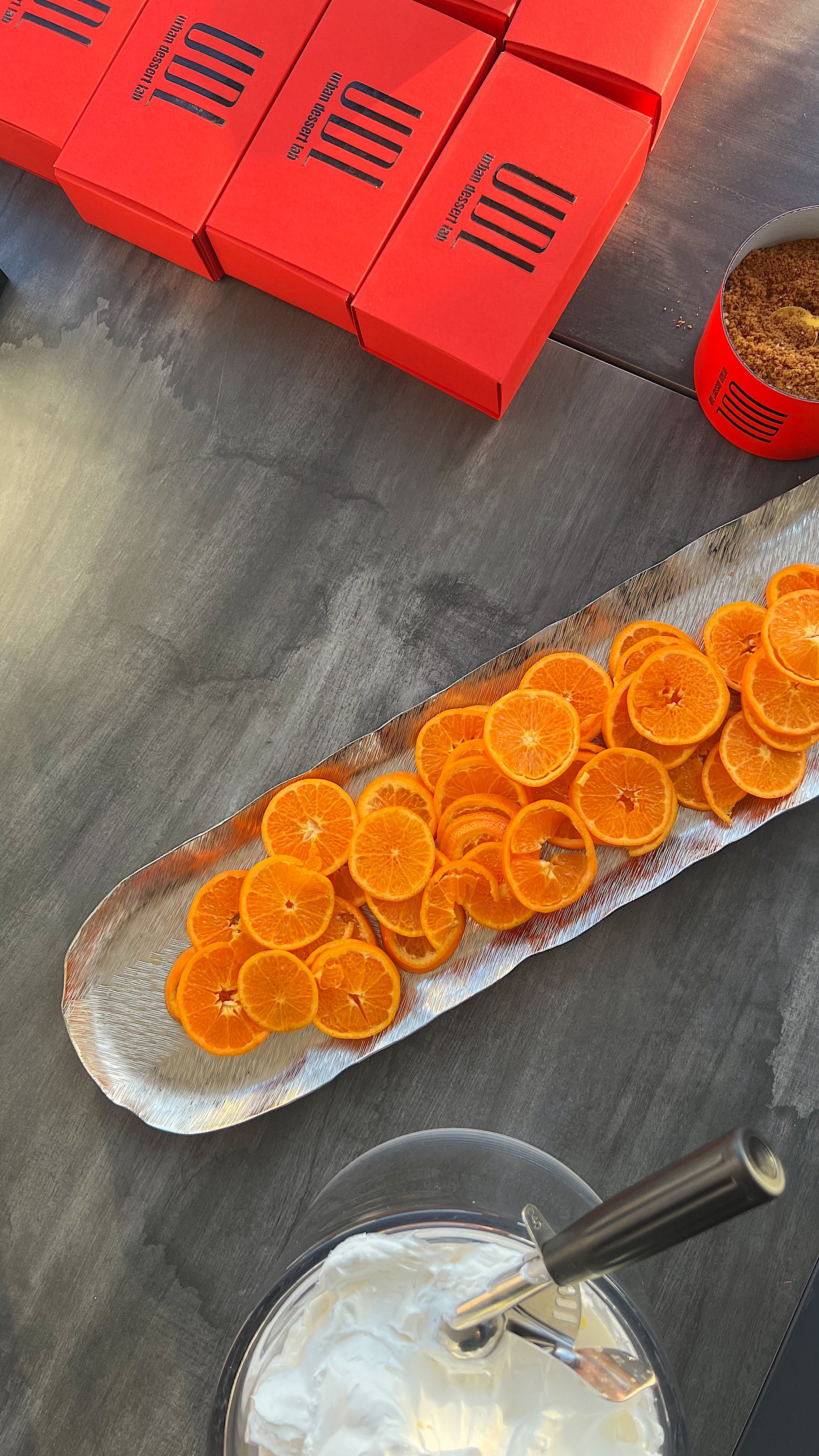Photo of Branded Red Urban Dessert Lab boxes, orange slices on a tray and a bowl of dessert creme