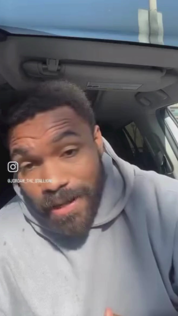 Jordan Stallion is speaking about Urban Dessert Lab from inside a car, wearing a gray hoodie. Sunlight is visible through the car window.